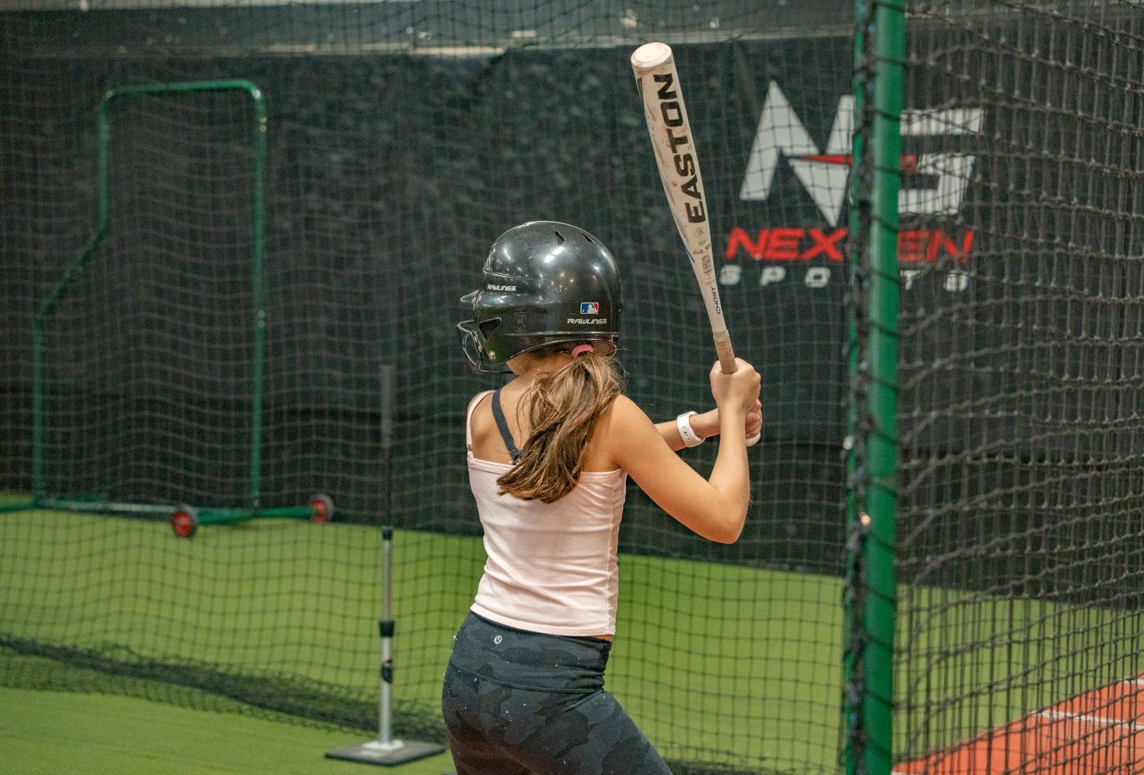 Young athlete training in a batting cage at NexGen Sports